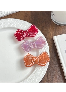 Detailed macro view of three marbled acrylic bow hair clips in pink, purple and orange colors