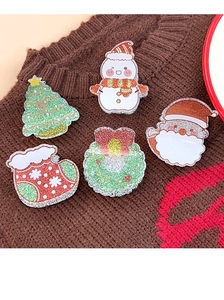 Nahaufnahme von fünf glitzernden Weihnachts-Acryl-Pins auf einem braunen Strickpullover