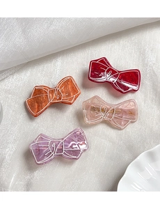 Detail of four glitter resin bow hair clips in multiple colors with gold metal grip