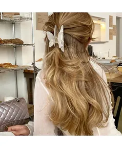Détail d'une pince à cheveux papillon nacrée élégante avec strass sur cheveux ondulés