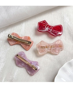 Detailed macro view of four acrylic butterfly hair clips in elegant pastel glitter finishes