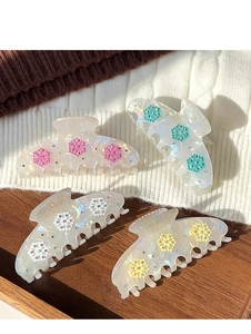 Detail of four iridescent snowflake hair claws with rhinestones on a cable knit sweater