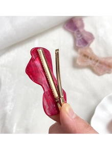Close-up of red marble pattern acetate bow hair clip with gold metal grip detail