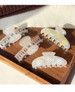 Macro detail of pearlescent snowflake hair claws with floral crystal accents on wood