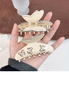 Détail de pinces à cheveux papillon crème avec strass et motifs évidés à la main