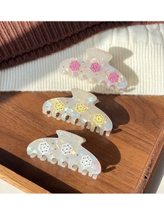 Close-up of elegant snowflake hair claws in pink, yellow and white acetate with rhinestones