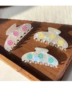 Close-up of three pearlescent snowflake hair claws with colorful flowers and rhinestones
