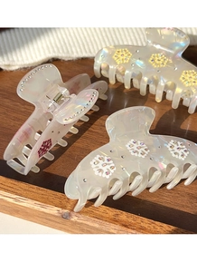Close-up of three iridescent resin snowflake hair claws with sparkling rhinestone accents