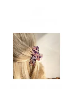 Détail d'une pince à cheveux en acétate marbré violet sur des cheveux blonds ondulés