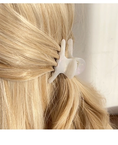 Primer plano de una pinza para el cabello de acetato blanco perlado en pelo rubio