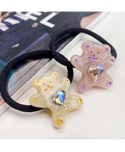 Close-up of cute cartoon bear hair ties with colorful heart rhinestones on a white background