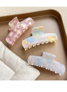 Trois pinces à cheveux en acétate avec motifs floraux et marbrés sur un plateau