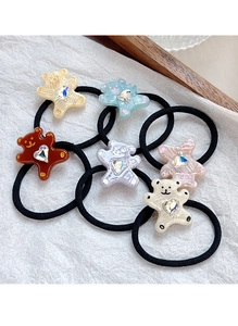 Close-up of six colorful bear hair ties with crystal hearts on a white background