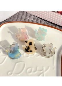 Set of five colorful marble texture acetate cat hair clips displayed on a white ceramic plate