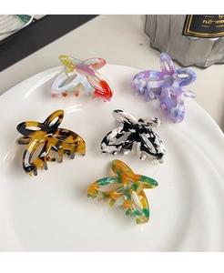 Detailed top view of five hollow acetate butterfly hair claws with varied artistic patterns