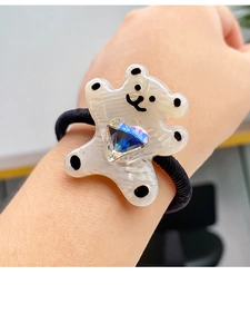 Detailed close-up of a cute acetate bear hair tie with a blue crystal heart on a wrist