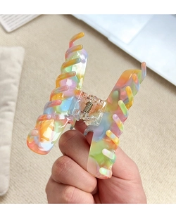 Détail de la pince à cheveux arc-en-ciel en acétate montrant la texture résine et le ressort