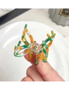 Detail view of a translucent acetate butterfly hair claw with marble texture and metal spring