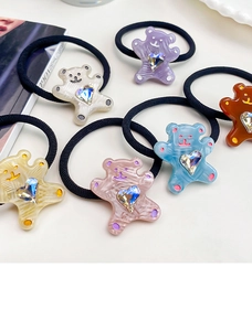Detail shot of colorful bear hair ties with heart rhinestones on a white surface