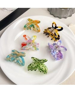 Detailed view of six colorful hollow butterfly hair claws in a white ceramic plate