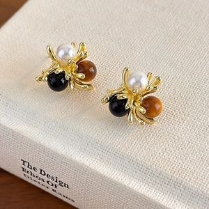 Vintage gold stud earrings with marble amber, pearl, and black beads on white book