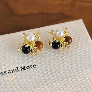 Detailed macro view of vintage gold insect-shaped stud earrings with amber beads