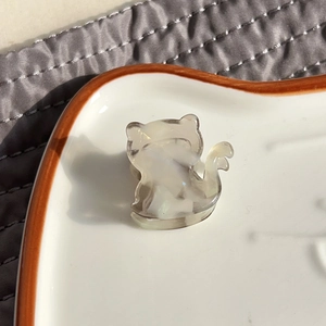 Pinza per capelli a gatto in acetato beige con trama a conchiglia su piatto