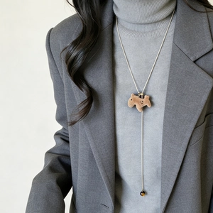Brown flocked puppy pendant long sweater necklace on model with grey turtleneck