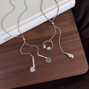 Detailed close-up of a silver headphone and tennis racket pendant on a sleek snake chain
