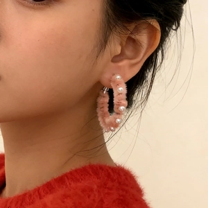 Boucles d'oreilles créoles roses en peluche avec perles blanches sur un modèle féminin