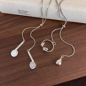 Detail of silver headphone and tennis racket pendants on a sleek snake chain necklace
