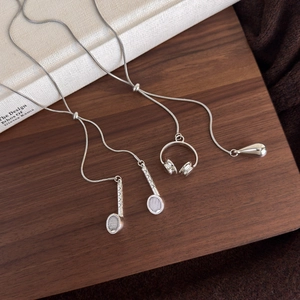 Silver long necklace with tennis racket, headphone, and teardrop charms on snake chain