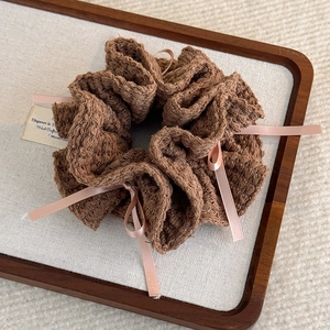 Vue détaillée d'un chouchou en tricot marron avec des rubans roses et des petits nœuds