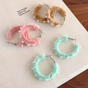 Détail de créoles en peluche marron, rose et vert menthe avec perles décoratives