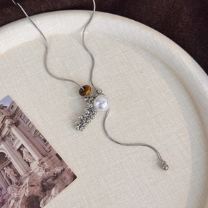 Detail of tiger eye stone and pearl pendant on a silver snake chain sweater necklace