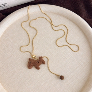 Detail of the brown flocked pony pendant with golden chain and bead on a tray