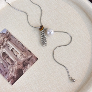 Detail of Y-shaped necklace with tiger eye stone and large white pearl pendant