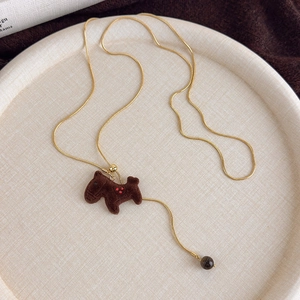 Macro view of golden snake chain necklace with brown flocked puppy pendant and bead detail