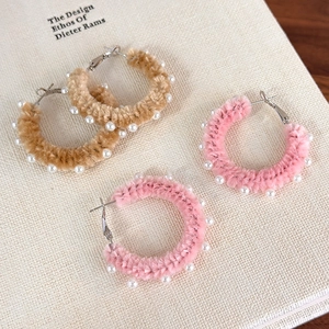Gros plan sur des boucles d'oreilles en peluche avec perles blanches en rose et beige
