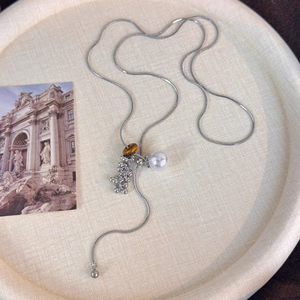 Detailed close-up of tiger eye stone and white pearl pendant on a silver snake chain