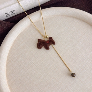Detail of a brown flocked puppy pendant with heart embroidery on a golden chain