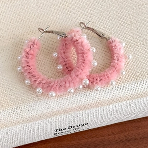 Gros plan de boucles d'oreilles créoles en peluche rose avec perles décoratives