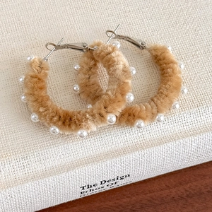 Détail montrant la texture velours camel et les perles blanches sur les créoles