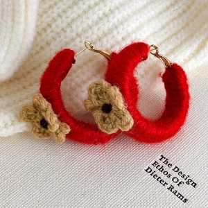 Gros plan de boucles d'oreilles créoles rouges au crochet avec fleurs marron tricotées
