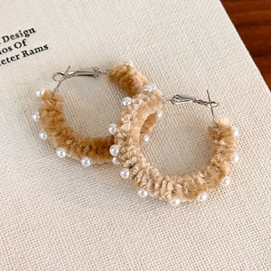 Vue macro de boucles d'oreilles créoles en peluche marron avec perles pour l'automne