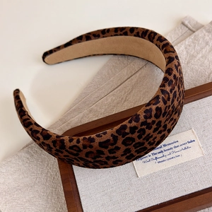 Detail of wide leopard print headband with soft velvet texture on a wooden display
