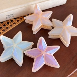 Pinzas para el pelo con forma de estrella en azul y rosa perlado sobre fondo de madera
