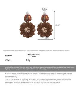 Detail view of brown knitted flower earrings with white imitation pearl studs and embroidery