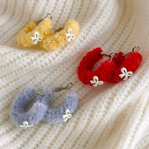 Boucles d'oreilles créoles en peluche colorée avec nœuds sur fond en maille douce
