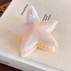 Detalle de una pinza para el pelo de estrella crema con facetas perladas sobre libro
